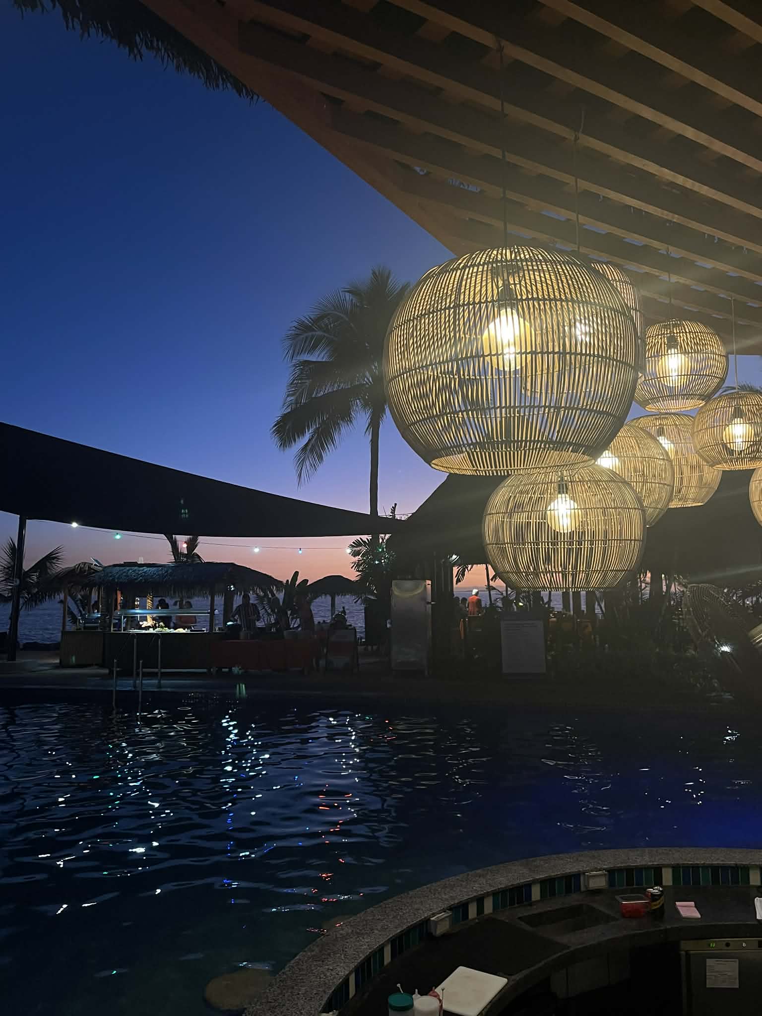Kokomo Private Island at night with pool lanterns, palm trees, and starry sky